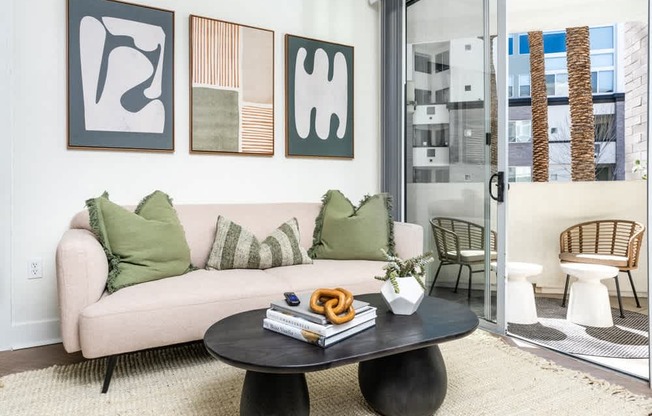 A living room with a couch, a coffee table, and three framed artworks on the wall.