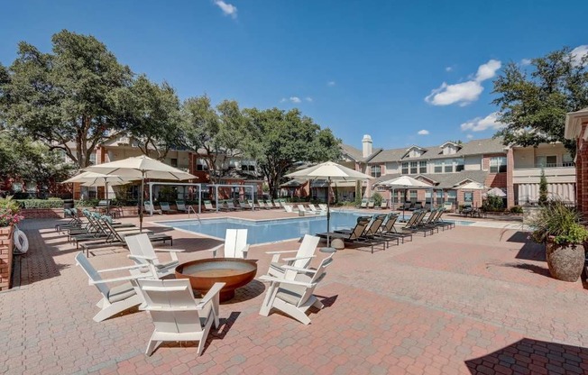 a large pool with chairs and umbrellas and a building in the background