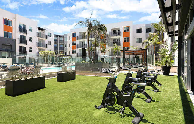 a group of exercise machines on a lawn in front of an apartment building
