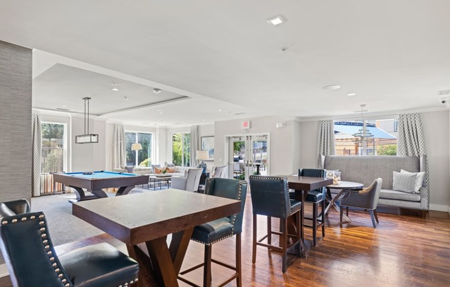 a common area with tables and chairs and a lounge area with couches and a pool table