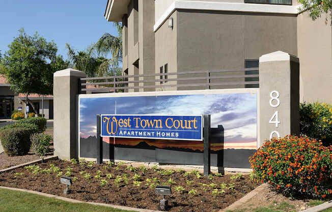 A sign for West Town Court Apartment Homes sits in front of a building.