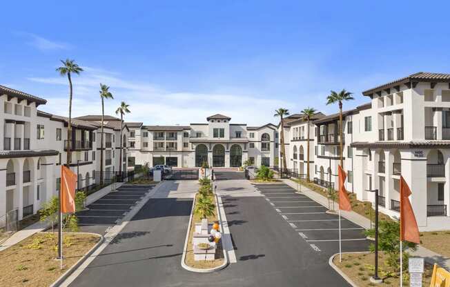 an empty street in front of apartments with palm trees