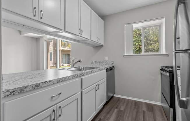 an empty kitchen with white cabinets and stainless steel appliances