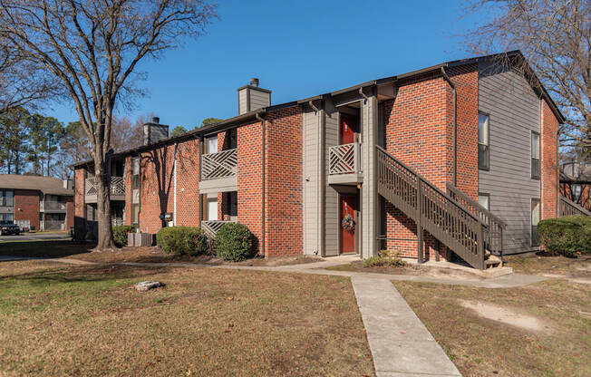 A brick building with a red door and a balcony.