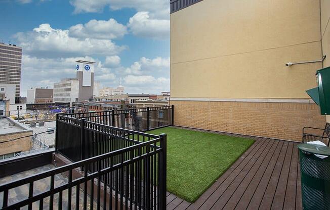 a balcony with green turf and a view of the city