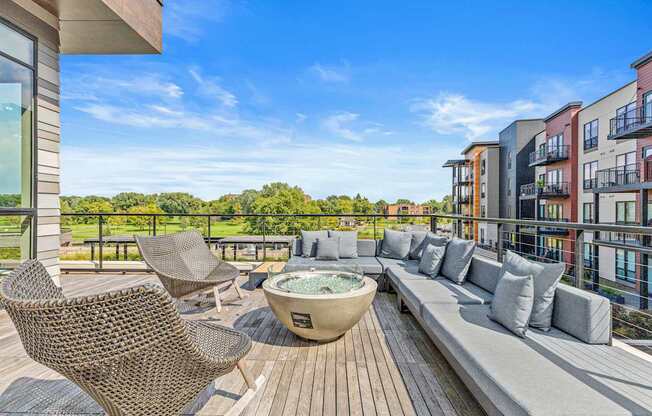 A patio with a hot tub and chairs overlooks a row of buildings.