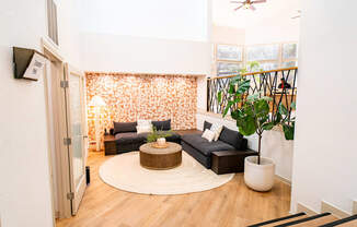 A living room with a black couch and a round wooden coffee table.