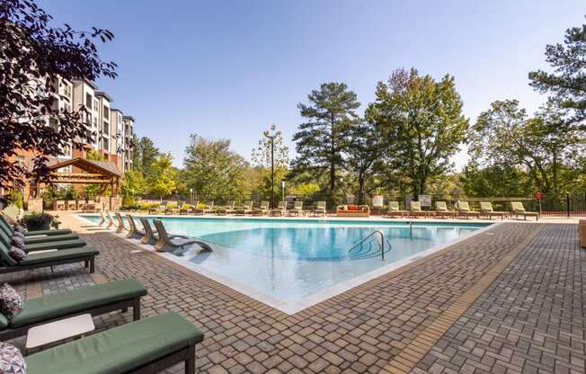 a swimming pool with chairs and a building in the background