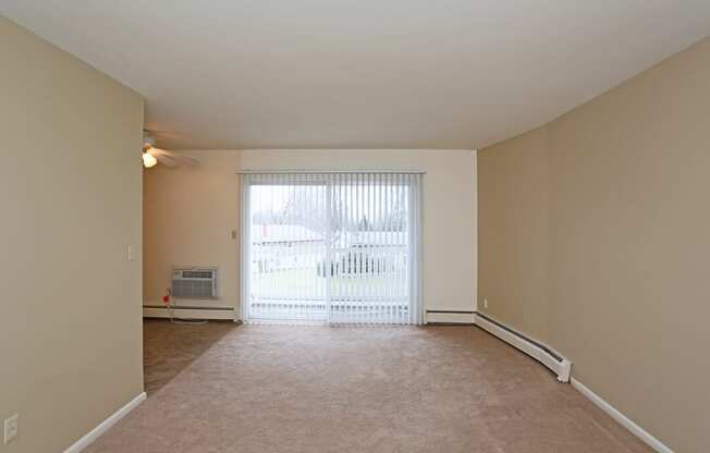 an empty living room with a large window and carpeting