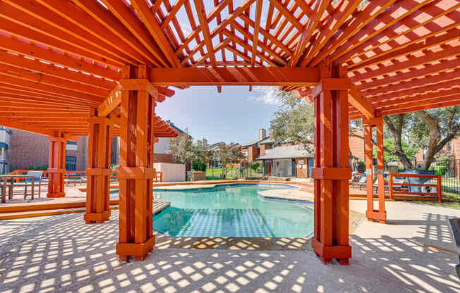 a backyard with a pool and a wooden pergola