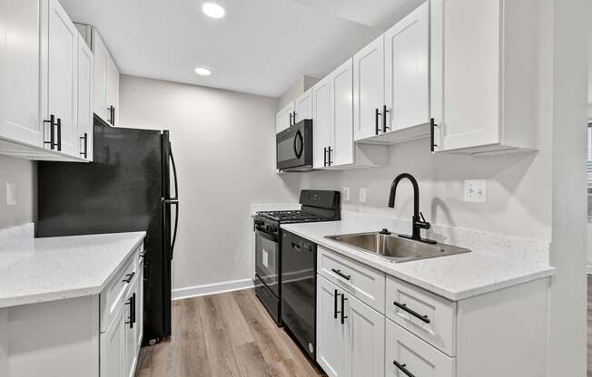 A kitchen with black appliances and white cabinets.