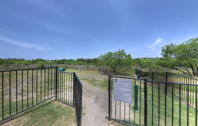 A sign is posted on a fence in front of a grassy area.