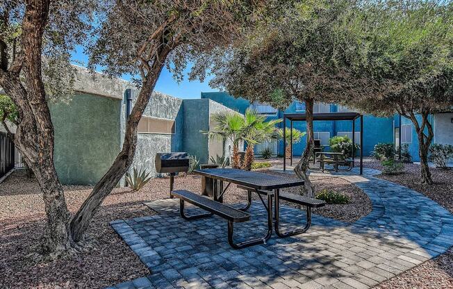 A picnic table is surrounded by trees in a courtyard.