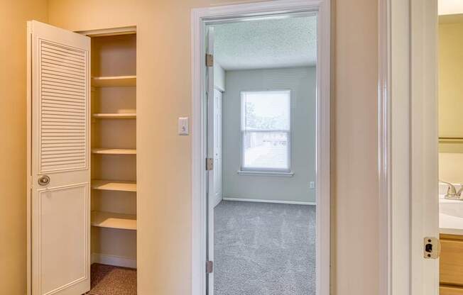 A white door is open to a room with a window and a sink.