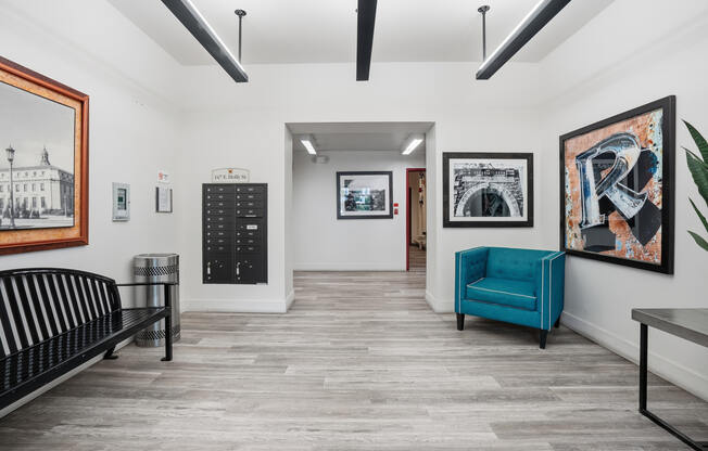 A room with a black bench, a blue chair, and a framed picture on the wall.