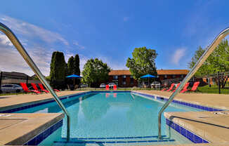 A swimming pool with a blue sky and trees in the background.