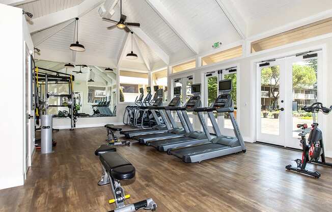 Gym with treadmills and ellipticals with screens weight bench, weight machine, rack and stationary bike