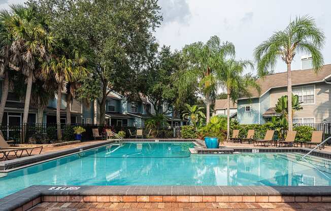 a swimming pool with palm trees in front of apartment buildings