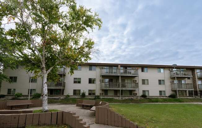 an apartment building with a lawn and a tree in front of it. Moorhead, MN South Park Apartments