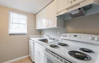 a kitchen with white cabinets and a white stove top oven at Del Rio Apartment