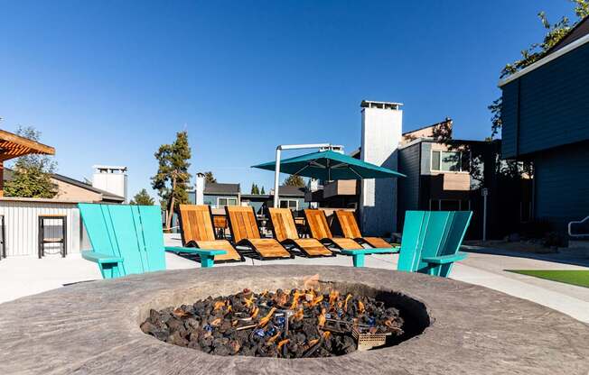 a fire pit with chairs and umbrellas on a patio