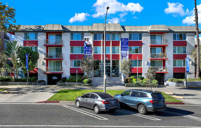 Two cars are parked in a parking lot in front of a red and white building.