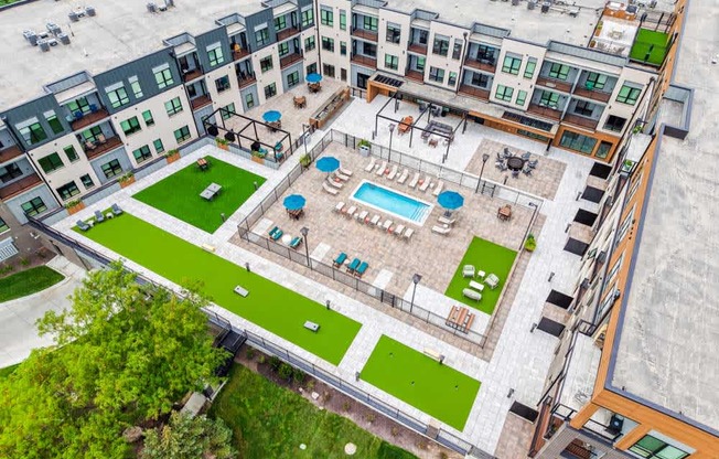An aerial view of a courtyard with a pool and outdoor yard games.