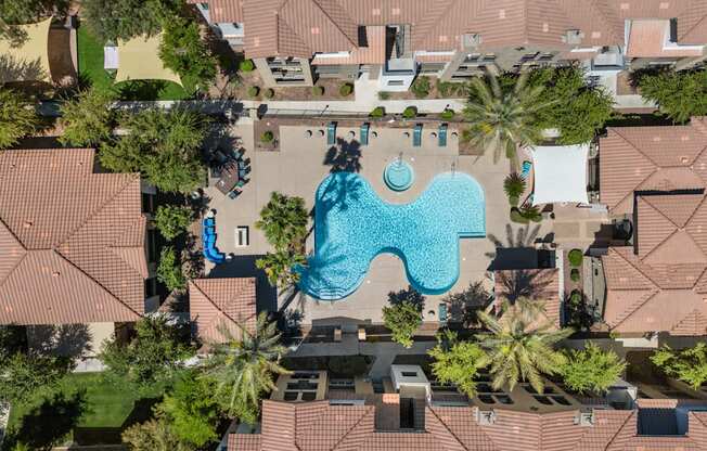An aerial view of a swimming pool surrounded by houses and trees.