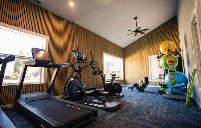 a woman sitting on the floor in a gym with weights and other exercise equipment