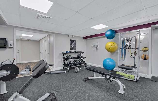 A gym with a variety of equipment including weights and exercise balls.