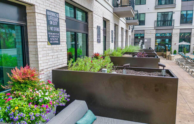 a seating area with a bench and flowers in front of a building
