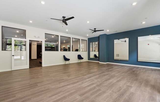 A spacious room with wooden floors and ceiling fans.