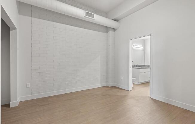 A white room with a brick wall and wooden floor. at Brickside Heights, Millcreek, Utah