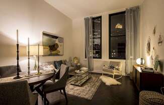 A well-lit living room with a dining table and chairs at The Pennsylvanian Apartments, Pittsburgh, PA