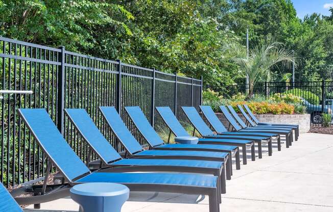 a row of blue lounge chairs in front of a black fence