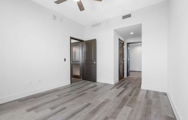 an empty living room with white walls and a ceiling fan