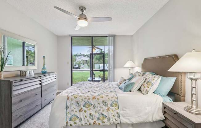 A bedroom with a bed, dresser, and ceiling fan.