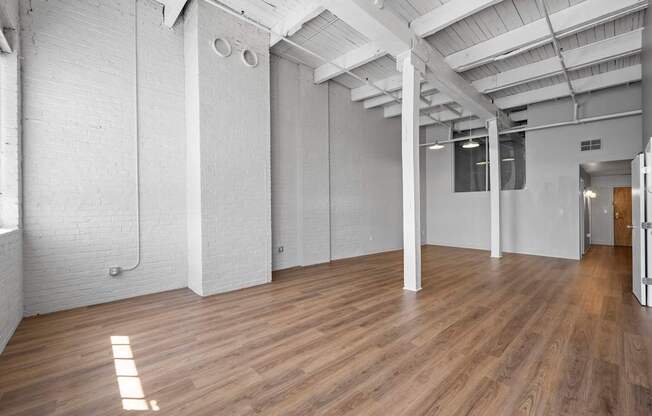 A spacious room with wooden floors and white walls.