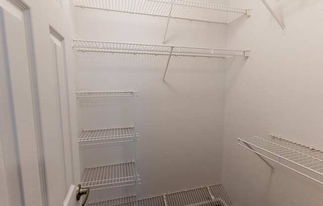 a white walk in closet with white shelves and a white door