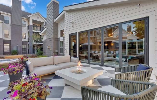 A patio area with a checkered floor, a fire pit, and chairs.
