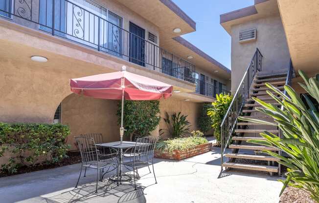 a patio with a table and chairs and an umbrella in front of a building