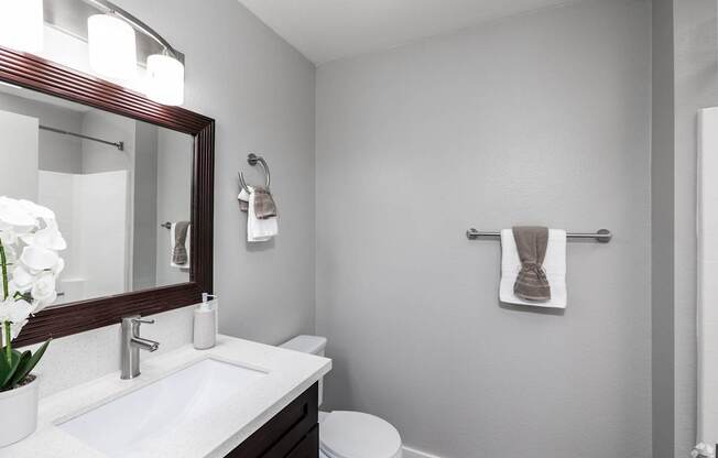A white sink with a mirror above it and a towel hanging on the wall.