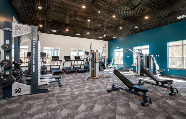 a gym with cardio equipment and weights in a building with blue walls