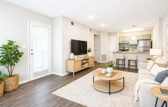 A living room with a white couch, a wooden coffee table, and a flat-screen TV.