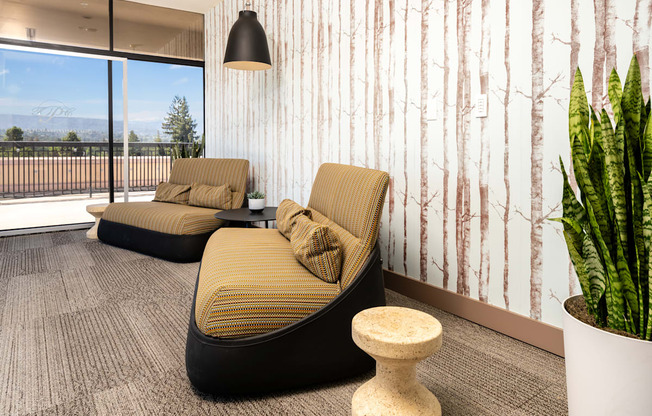 A room with two chairs and a table in front of a wallpapered wall.