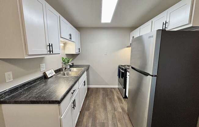 A kitchen with white cabinets and a black countertop.