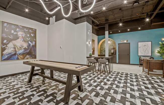 a game room with a shuffleboard table and a painting on the wall