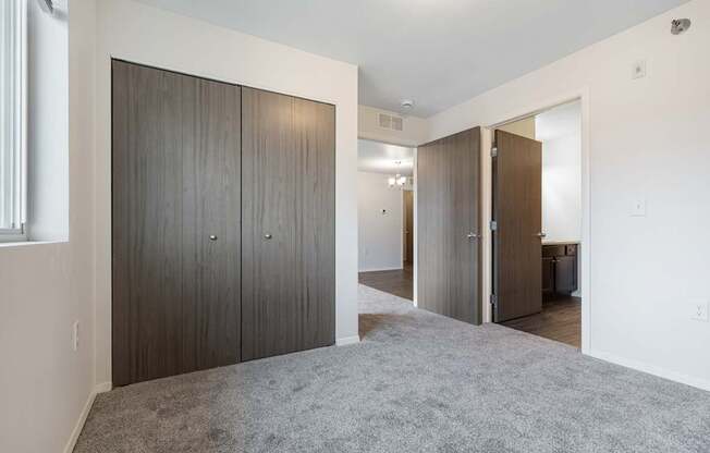 A room with a grey carpet and a wooden wardrobe.