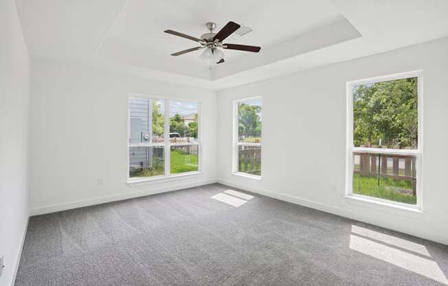 A room with a ceiling fan and two windows.
