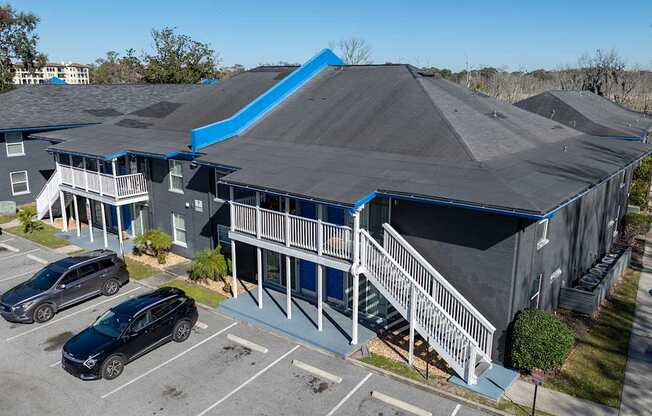 A large grey building with a blue roof and a parking lot in front at Mandarin Bay Apartments on San Jose Blvd